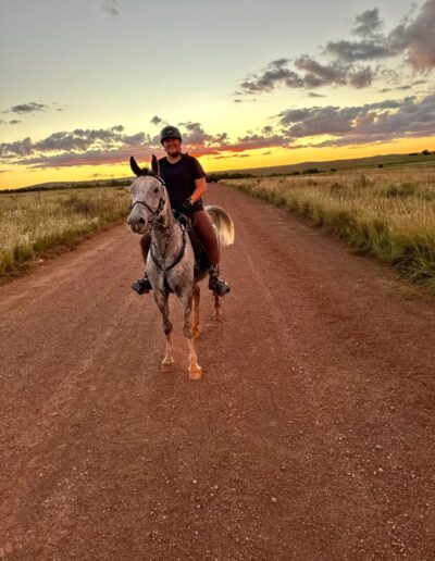 Anri riding at golden sunset on a red dirt road